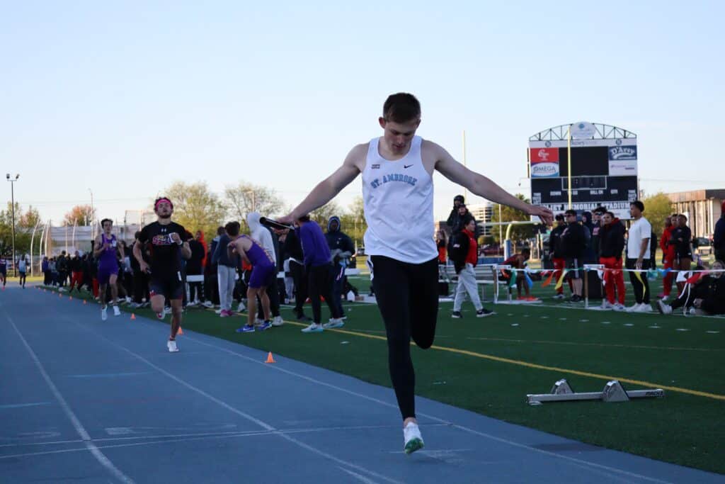 A man is finishing a race on a track while others watch.