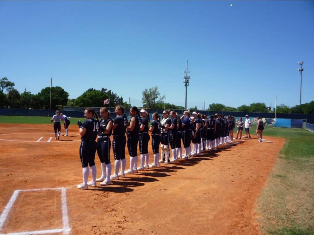 A group of female softball players standing on the field.