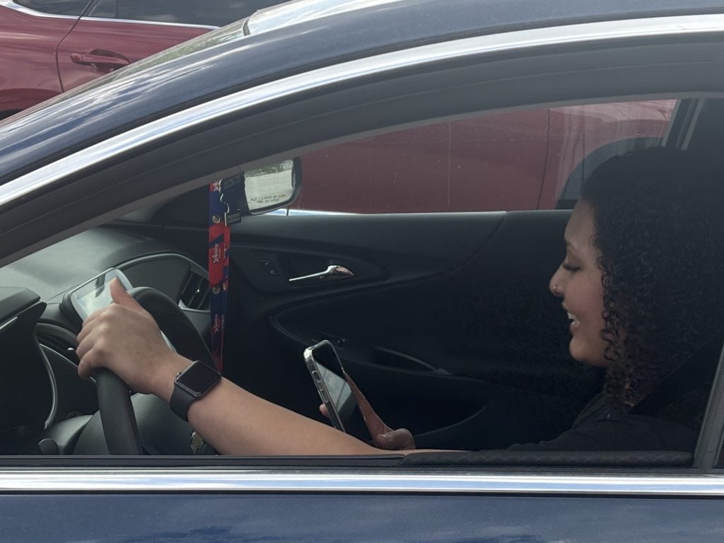 Young Driver with phone in hand at the wheel of a car.