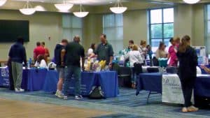 Students explore mental health resources at the university fair in a spacious hall.