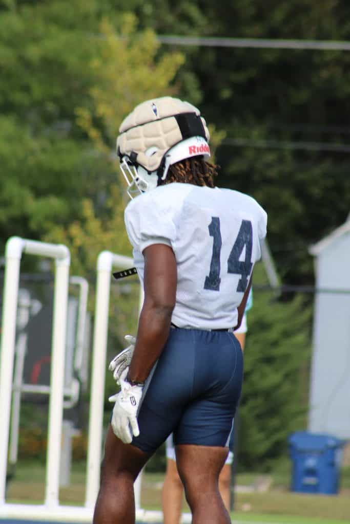Football player wearing helmet and jersey number 14 on the field.