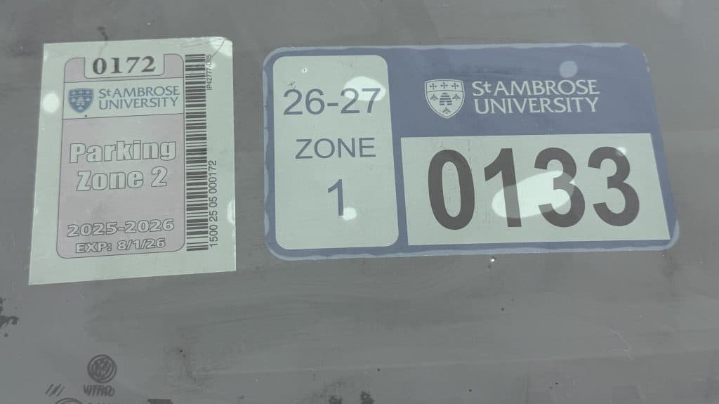 Stambrose University parking permit and zone sticker on vehicle windshield.