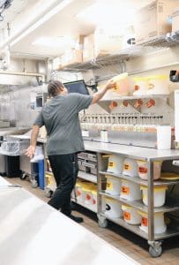 Kitchen staff preparing food and drinks in a busy restaurant kitchen.