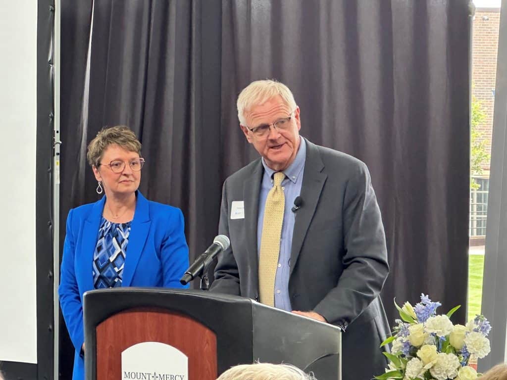 Two speakers at a podium during a formal event at Mount Mercy University.