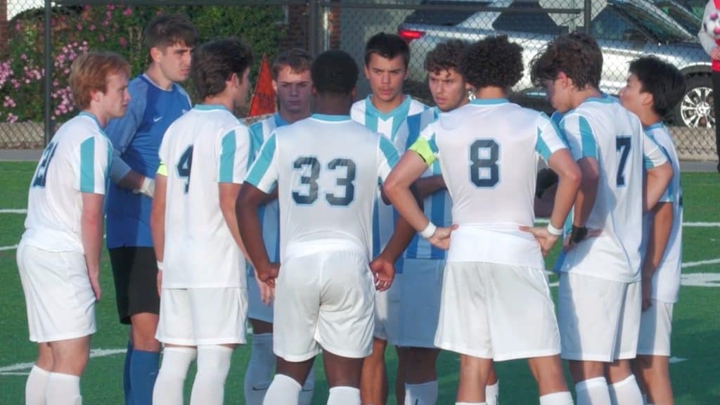 Youth soccer team huddles on the field during a game or practice session.