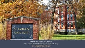 St. Ambrose University campus sign with brick building and autumn trees.
